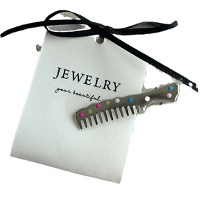 Comb shaped silver hair clip with colorful polka dots and a metal alligator grip