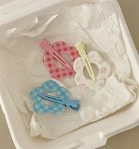 Close-up of sweet flower hair clips in pink and blue plaid patterns with metal duckbill clips