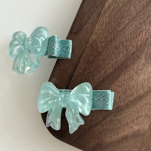 Détail de deux pinces à cheveux avec nœuds en gelée vert menthe et motifs en tissu