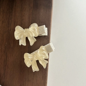 Détail de barrettes à cheveux nœud en résine beige translucide avec ruban rayé