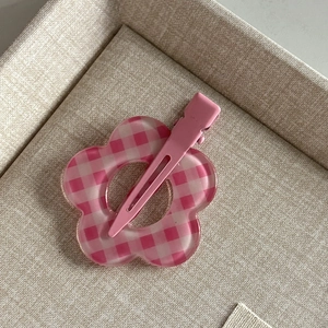 Detailed close-up of a pink gingham pattern flower hair clip with a metal duckbill clip