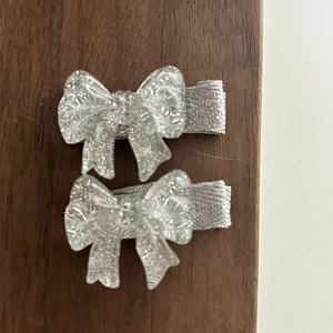 Vue détaillée de deux pinces à cheveux nœud à paillettes argentées avec ruban gris
