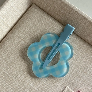 Detail view of blue and white checkered flower hair clip with a sturdy duckbill base