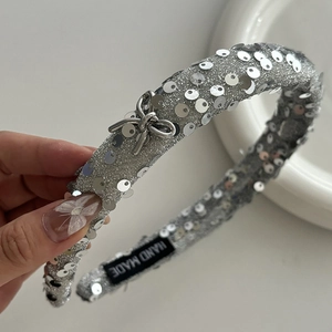Silver sequin headband with metal bow and handmade label on elegant white background