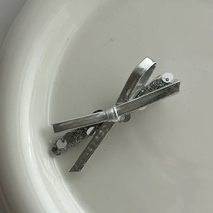 Macro detail of a silver sequined bow hair clip showing sparkling textures and craftsmanship