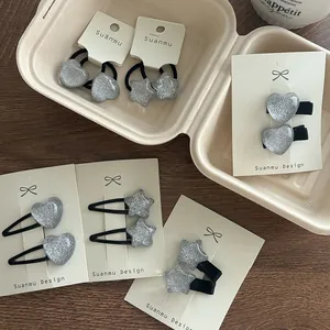 Détail de pinces à cheveux et élastiques argentés pailletés en forme de cœur et étoile