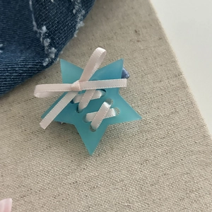 Détail d'une pince à cheveux étoile bleu clair avec un nœud papillon en ruban rose