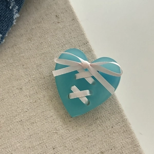 Pince à cheveux cœur bleu clair avec ruban blanc sur un fond en lin texturé élégant