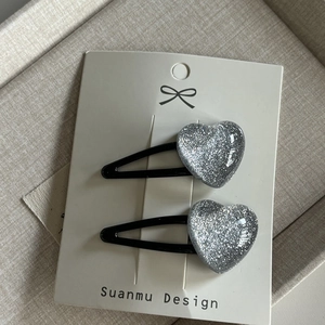 Détail de barrettes à cheveux en forme de cœur pailleté argenté sur carte de support