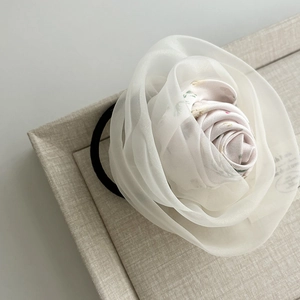 Detail of floral hair tie with white organza petals and pink floral fabric core on linen