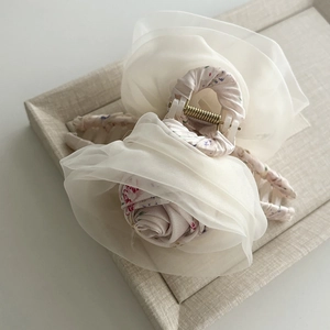 Detailed view of cream organza rose hair claw clip with floral fabric covering
