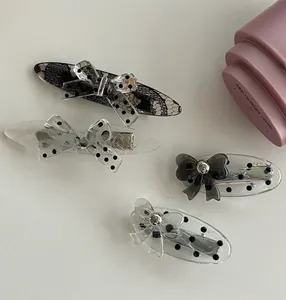 Detailed view of four acrylic hair clips with polka dot lace bows and metal duckbill clips