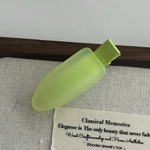 Simple bright green jelly hair clip with a translucent matte finish on canvas background