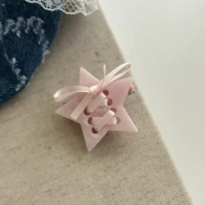 Gros plan d'une pince à cheveux étoile crème avec nœud en ruban rose style ballet