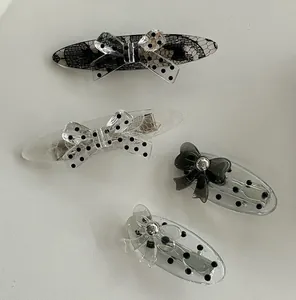 Detailed view of four acrylic polka dot lace bow hair clips with metal duckbill grips