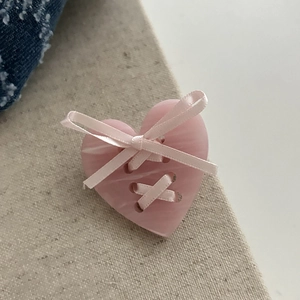 Vue détaillée d'une pince à cheveux cœur rose avec un nœud en ruban satiné au style mignon
