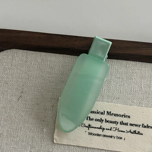 Minimalist light green matte hair clip for styling side bangs on aesthetic fabric backdrop