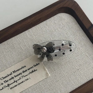 Minimalist polka dot acrylic hair clip with grey lace bow and silver bead on wood tray