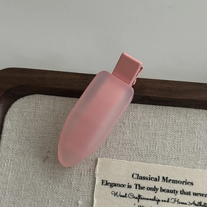 Detail of pink matte jelly hair clip showing duckbill structure on canvas background