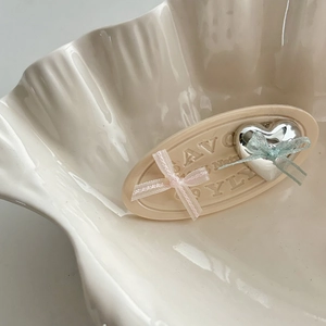 Pink ribbon bow hair clip with silver heart on a decorative cream bar in shell dish
