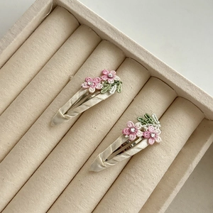 Dettaglio di fermagli per capelli con fiori ricamati rosa e strass su nastro beige