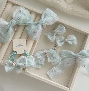 Détail de barrettes en tulle bleu clair avec strass roses sur un plateau beige