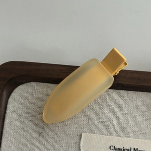 Close-up of matte translucent yellow duckbill hair clip on a neutral background