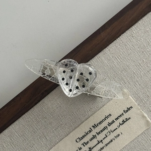 Close-up of heart-shaped acrylic hair clip featuring polka dot lace patterns and clear texture
