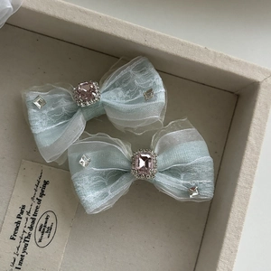 Détail des barrettes nœuds en dentelle bleu clair avec pierres roses et cristaux