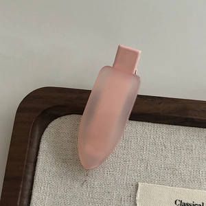 Close-up of translucent matte pink jelly hair clip on a minimalist wooden display stand