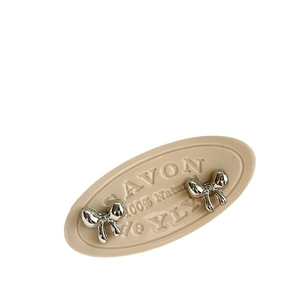 Pair of metallic silver bow stud earrings displayed on a minimalist beige decorative prop