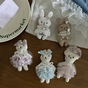 Handmade rabbit and bear fabric hair clips with lace skirts and pearl details on wood