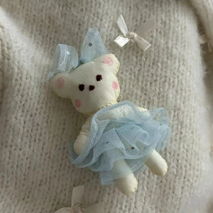 Detail of sweet handmade bear plush accessory with blue lace skirt on knitted fabric