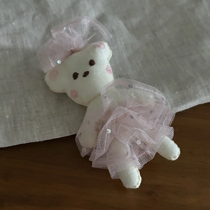 Detailed view of handmade plush bear charm with pink lace bow and ruffled tulle skirt