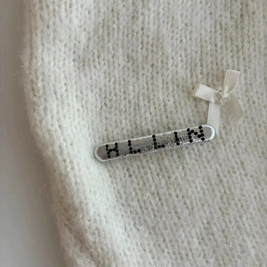 Barrette argentée avec perles ALLIN et nœud en soie blanche sur fond en tricot doux