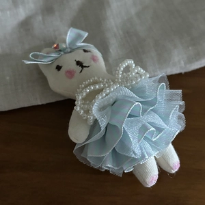 Close-up of cute plush bunny hair accessory with striped tulle dress and pearl necklace