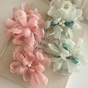 Close-up of pink and green mesh flower hair claws with pearls and ribbon bows