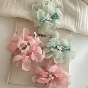 Detail view of mesh flower hair claws with pearls and satin bows on vintage books