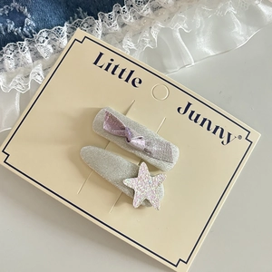Détail de barrettes argentées avec nœud violet et breloque étoile rose à paillettes