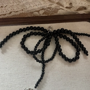 Détail d'un bijou de chaussure en perles noires avec fermoir mousqueton argenté