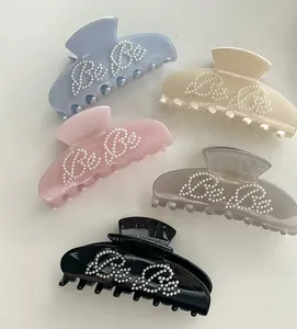 Detail view of five assorted pastel acetate hair claws with BeBe pearl lettering