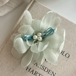 Detailed close-up of light green floral hair claw clip with pearls on a book