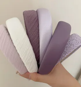 Gros plan de serre-têtes violets et blancs en tissu plissé et finitions satinées