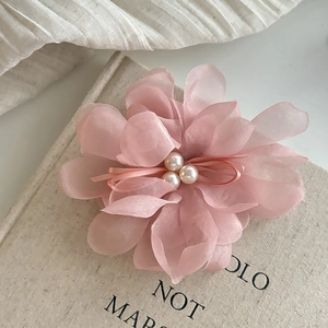 Elegant pink mesh flower hair claw with pearls for women styling over a book background