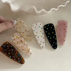 Close-up of five colorful rhinestone hair clips in marble and tortoise patterns