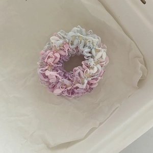 Dettaglio di un elastico per capelli in maglia pastello con filato morbido
