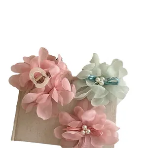 Elegant floral hair claw clips with pink mesh petals and pearls on a vintage book