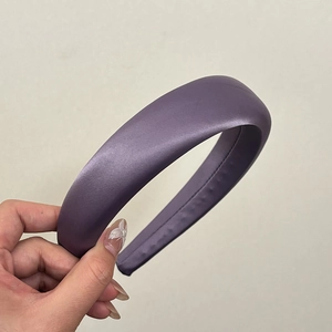 Gros plan d'un serre-tête large en satin violet rembourré avec une finition brillante élégante