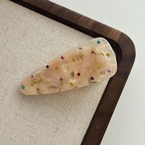 Creamy marble resin hair clip with colorful rhinestones on a wooden tray