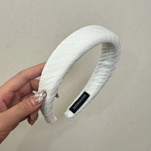 Détail du serre-tête éponge plissé blanc avec étiquette faite main et texture en tissu